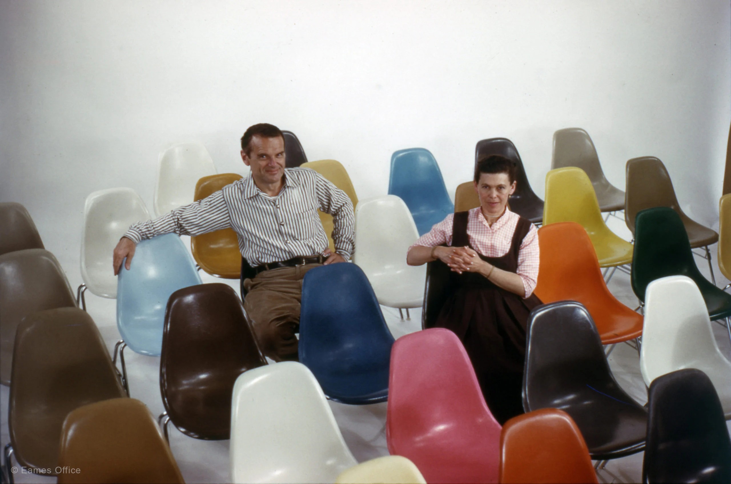 a man and woman sitting on colorful chairs.